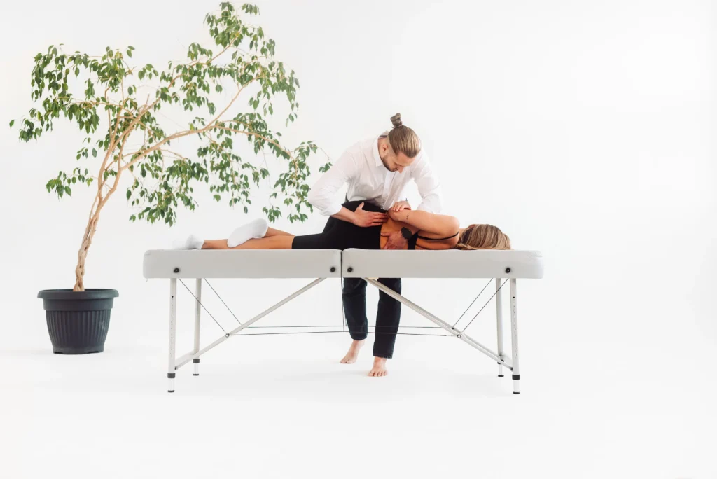 Zabieg fizjoterapeutyczny w gabinecie – terapeuta pracuje nad mobilnością kręgosłupa lub biodra pacjentki.