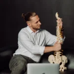 Diagnostyka bólu pleców w Uzdrovisko – specjalista wyjaśnia problem na modelu kręgosłupa.