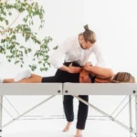 Fizjoterapeuta z Uzdrovisko wykonuje terapię manualną kręgosłupa u pacjentki leżącej na boku na stole do terapii.